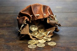 Swiss Vreneli gold coins in a leather purse on rustic wooden background