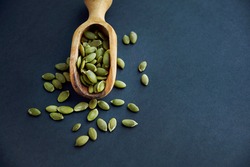 pumpkin seeds in a wooden bowl and vintage scoop. Close up on a black background. copy space for text