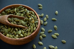 pumpkin seeds in a wooden bowl and vintage scoop. Close up on a black background. copy space for text