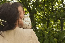 Enveloped by greenery, young mom swings her baby, their faces glowing in mutual admiration and contentment. Emotional Development of Infants: What Parents Should Know