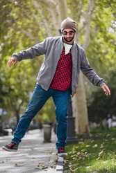Stylish balance act: Bearded gentleman, red-checks, exhibits poise on Madrid's sunny street.