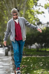 Autumn equilibrium: Bearded guy, red-checks, effortlessly balances on Madrid's sunny fence.