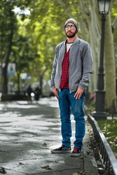Chic pose: Bearded gent in red-checks, beanie, defines Madrid's urban elegance.