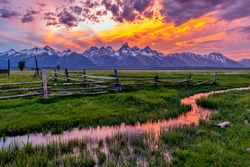 Golden Fiery Sunset at Grand Teton - A colorful spring sunset at Teton Range, seen from an abandoned old ranch in Mormon Row historic district, in Grand Teton National Park, Wyoming, USA. 