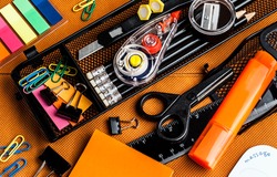 colorful school and office supplies on an orange background