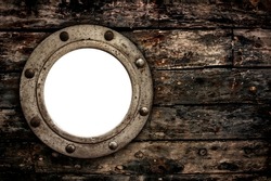 Close-up of an old rusty closed empty porthole window on old wooden planks from retro boat.
