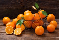 fresh orange fruits with leaves in a basket on wooden table