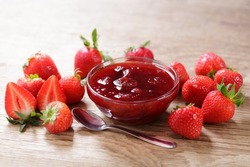 Bowl of strawberry jam with fresh fruits on wooden table