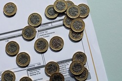 Pound Coins Resting On A Wage Slip. Increasing Tax And National Insurance Contributions Concept.