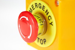 Red button in a yellow case with the label EMERGENCY STOP.