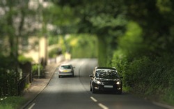 Cars traveling in the tunnel of trees. Typical Devonian road. Miniature Effect.