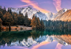 Impressive Autumn landscape during sunset.  The Fusine Lake in front of the Mongart under sunlight. Amazing sunny day on the mountain lake. concept of an ideal resting place. Creative image.