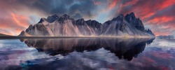 Vestrahorn mountaine on Stokksnes cape in Iceland during sunset with reflections. Amazing Iceland nature seascape. popular tourist attraction. Best famouse travel locations. Scenic Image of Iceland
