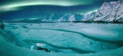 Northern lights (Aurora borealis) in the sky over snow covered mountains range and river. Fantastic nature scenery. Wonderful winter landscape. Lofoten islands. Norway. Christmas travelling concept