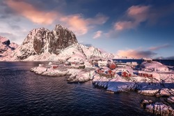 Stunning athmospheric scenery. Fantastic winter landscape during sunset. wintry nature background. Landscape with snowy rocks, colorful sky, reflection in water, fjord. Lofoten Islands. Reine. Norway