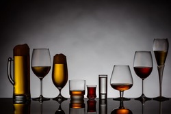 different glasses of alcoholic drinks backlit with reflection