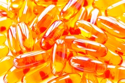 Biological additives to food, vitamins for a healthy lifestyle, capsules an omega 3 with cod-liver oil, transparent orange color an embankment on a light background close up