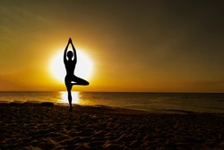 Vrikshasana tree pose from yoga by woman silhouette on sunset