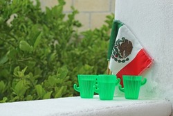Mexican flag and small tequila plastic glasses. Independence Day.