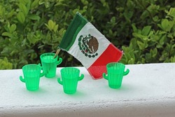 Mexican flag and small tequila plastic glass. Independence day.