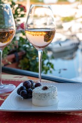 Tasting of local rose wine and soft french goat cheese in summer with sail boats haven of Port grimaud on background, Provence, Var, France