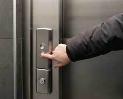 Lift button pressing. Elevator buttons pushing, forefinger pressing on down button, finger touching metal control panel on wall