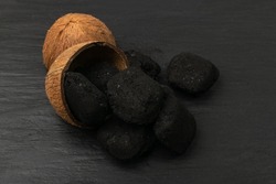 Coconut coal briquette on black background. Pressed charcoal for braai, coconut barbecue coal, bbq briquettes, grill charcoal top view