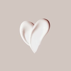 cosmetic smear of cream in the shape of heart on beige background 