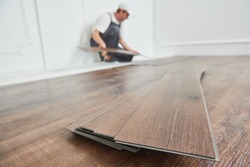 worker laying vinyl floor covering at home renovation