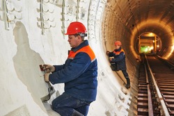 Tunneller worker installing fixture in underground subway metro construction site