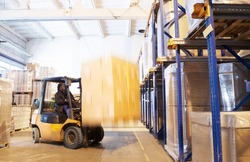 worker driving a forklift loader in warehouse with load