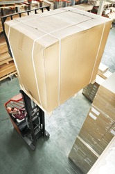 warehouse stacker forklift lifting large cardboard box