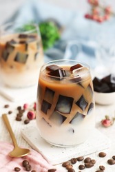A glass of iced milk latte with fresh homemade Japanese coffee jelly with its bean in background. It's a dessert flavored with coffee, gelatin and sugar.
