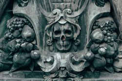 Medieval ornament with symbols of death and skull on a tombstone in a cemetery.