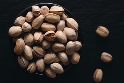 Roasted pistachios on the dark background. Dark food photography. Top view.