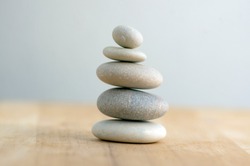 Stone cairn on striped grey white background, five stones tower, simple poise stones, simplicity harmony and balance, rock zen sculptures