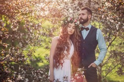 Beautiful bride with long hair and a bearded groom embracing. Newlyweds.