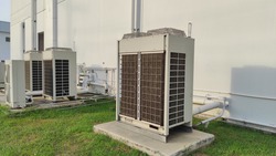 Air conditioning out door,A group of three industrial sized air conditioners along a brick wall,Air conditioning with extra door for maintenance