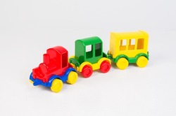 Multicolored children's plastic train. Toy locomotive with wagons on a white background.