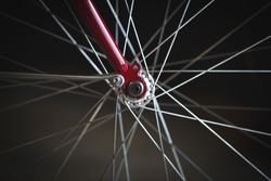 Closeup image shows details of spokes and gears on a red bike.