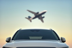 Parked Car in airport with taking off airplane on sky background. Transfer concept.