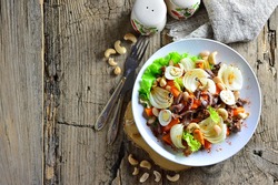 Warm salad with carrots, meat, quail eggs, cashew nuts, baked onion, top view, with spices, copy space