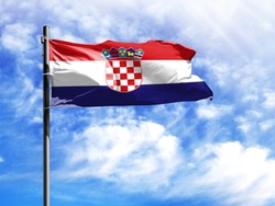 National flag of Croatia on a flagpole in front of blue sky.