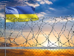 A fence with barbed wire against the background of a colorful sky and a flagpole with the flag of Ukraine protects the state's border from illegal migration.