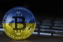 Bitcoin close-up on keyboard background, the flag of Ukraine is shown on bitcoin.