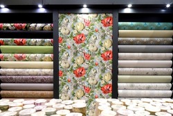 Rolls of vinyl wallpaper in building materials store. Various textures and colors as background. Wallpaper with floral pattern for wall, repair materials.