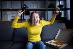 Cute girl plays the game on the console and eats pizza