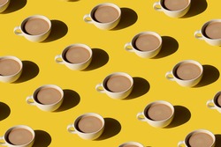 White cup of coffee with milk pattern on yellow background. Sunlight minimal trendy concept
