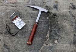 Geologists compass on the stones with hammer. Geology science concept. The geologist's hammer and tools are laid out on a stone while filedwork