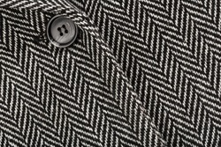 Herringbone tweed background with close up on wool fabric texture. Tweed, Wool Background Texture. Buttons placed diagonally on a herringbone pattern wool jacket. Herringbone (Broken Twill Weave). 